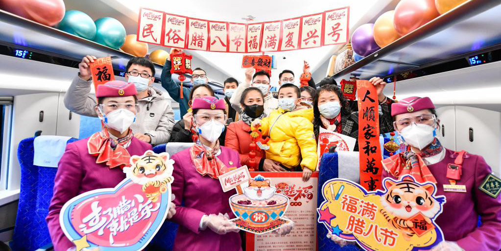 Membros de tripulação e passageiros celebram o Festival Laba em trem bala de Guiyang a Chengdu